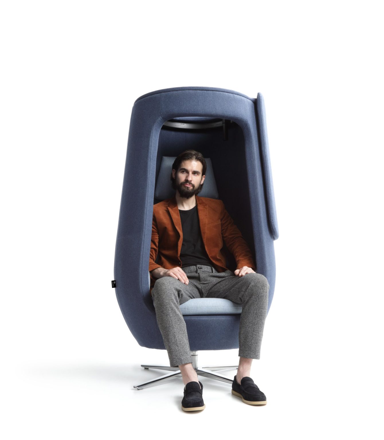 Man sitting in the open A11 armchair, cocoon-like shell around him
